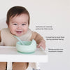 Baby using a green bowl and spoon with text describing features on a white background