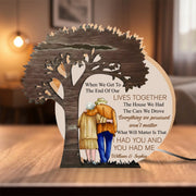 Wooden tree-shaped decoration with cut-out figures of a couple and engraved text on a wooden surface.