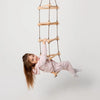 Child playing with a wooden climbing ladder on a plain background